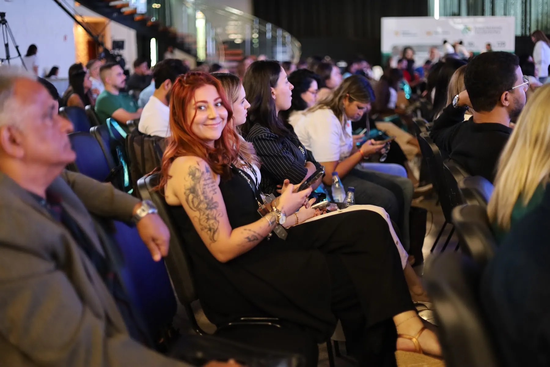 Pessoas acompanham uma programação sentadas em um auditório
