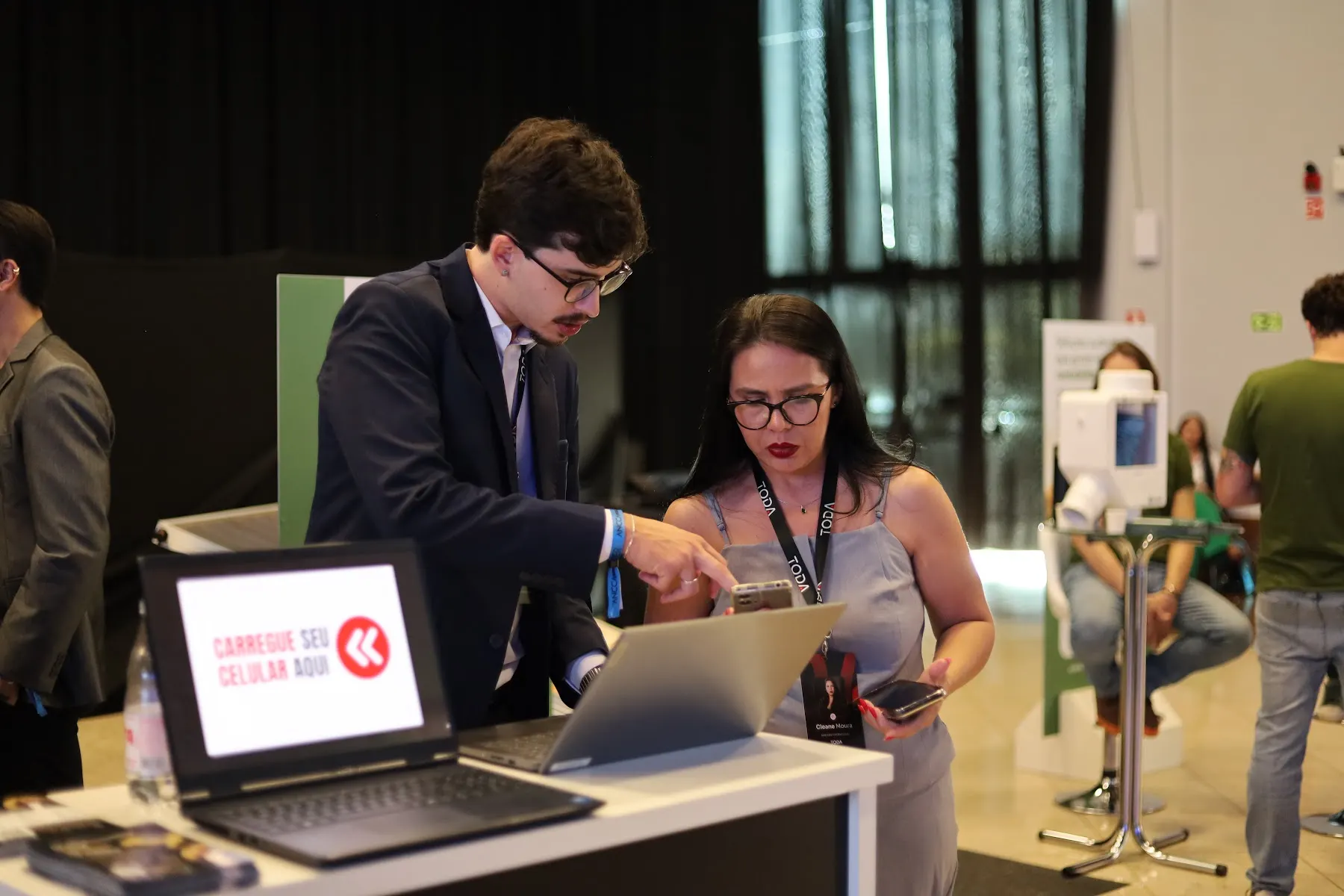 Um profissional e uma participante observam a tela de um notebook em um evento